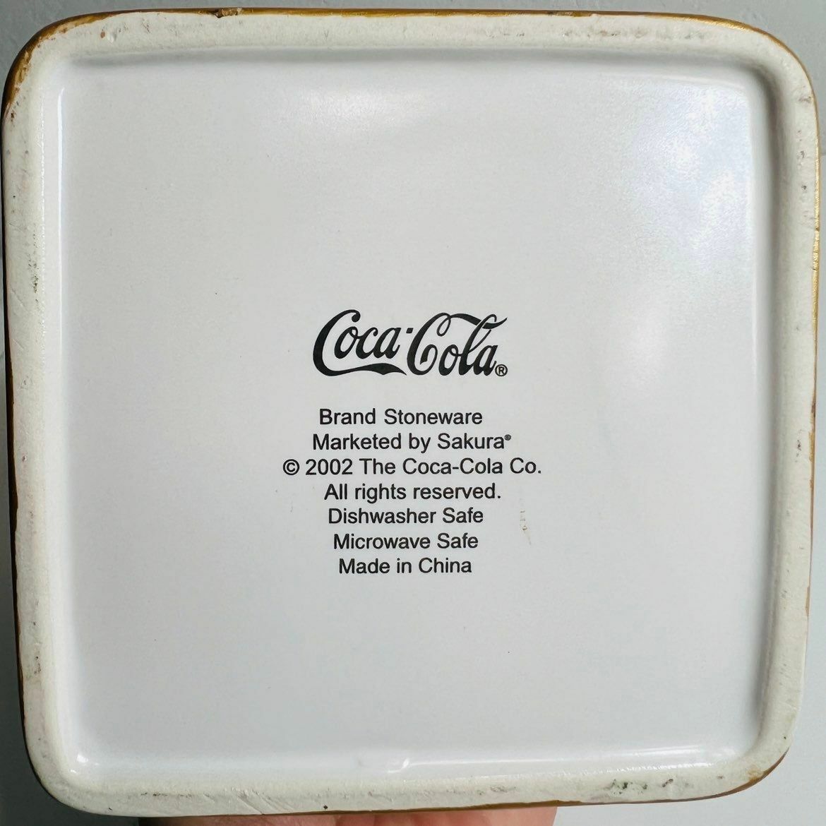 a person holding a white plate with a coca cola advertisement on it